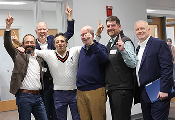 A group of men holding up one finger and smiling. Links to Gifts from Retirement Plans