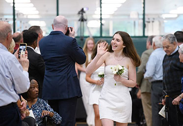A girl in a white dress waving at the crowd next to her. Links to Gifts of Real Estate