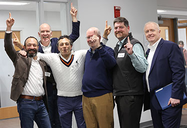 A group of men holding up one finger and smiling. Links to Gifts from Retirement Plans
