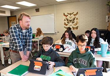 A teacher with students in a classroom. Links to Gifts by Will